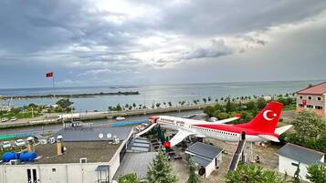 An airport terminal with a red and white airplane parked outside, surrounded by buildings and a road.