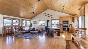 Relax in this inviting open-plan living area with a high ceiling and large windows offering views of the surrounding landscape.