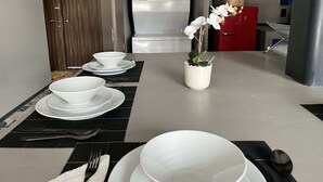 A kitchen with a white refrigerator, a red cabinet, and a dining table set with white plates, bowls, and cutlery. - Increible depto en la Condesa cama King Size (Ciudad de México)