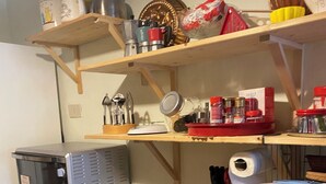 Una cuina amb prestatges de fusta que contenen diversos objectes de cuina, un microones i una màquina de cafè.