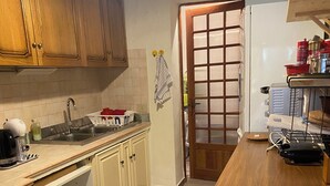 Cuina amb armaris de fusta, un rentaplat de stainless steel i una encimera de fusta.