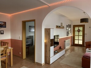 A living room with a TV, a fireplace, and a door leading to another room. - Urlaub im Herzen der Lausitz (Groß Düben)