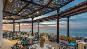 Un área de comedor al aire libre con mesas y sillas, con vistas al mar.