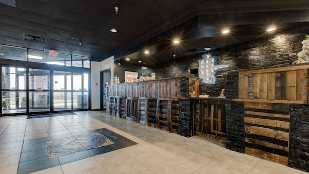 A spacious lobby with a modern design, featuring a stone and wood bar, large windows, and a tiled floor. - Hotel Lex and Conference Center, Trademark Collection (Lexington)