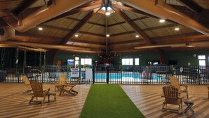 An indoor pool area with a wooden ceiling, a fenced swimming pool, and several Adirondack chairs. - Hotel Lex and Conference Center, Trademark Collection (Lexington)