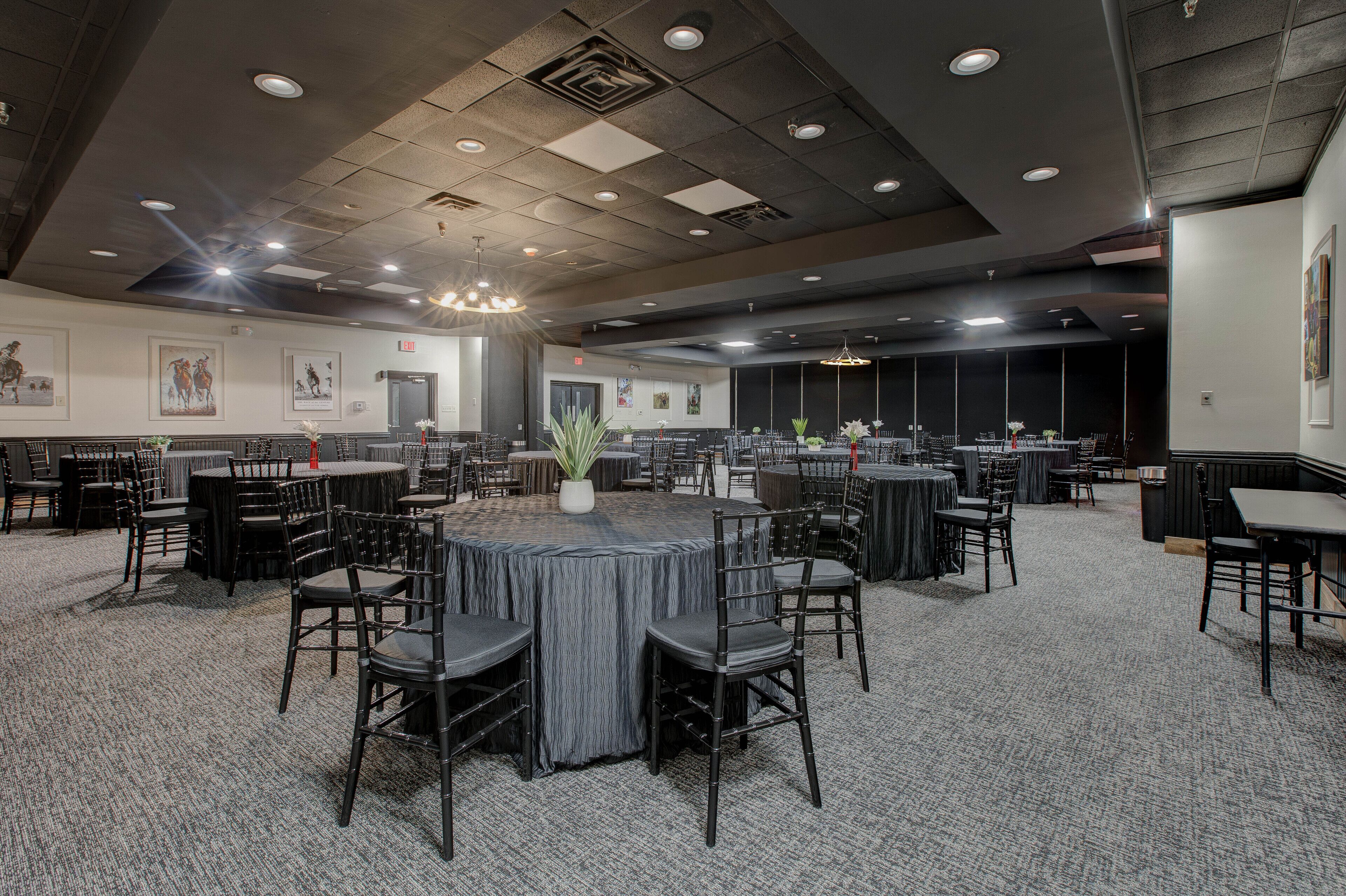 A large conference room with multiple tables and chairs, a central plant, and framed artwork on the walls.