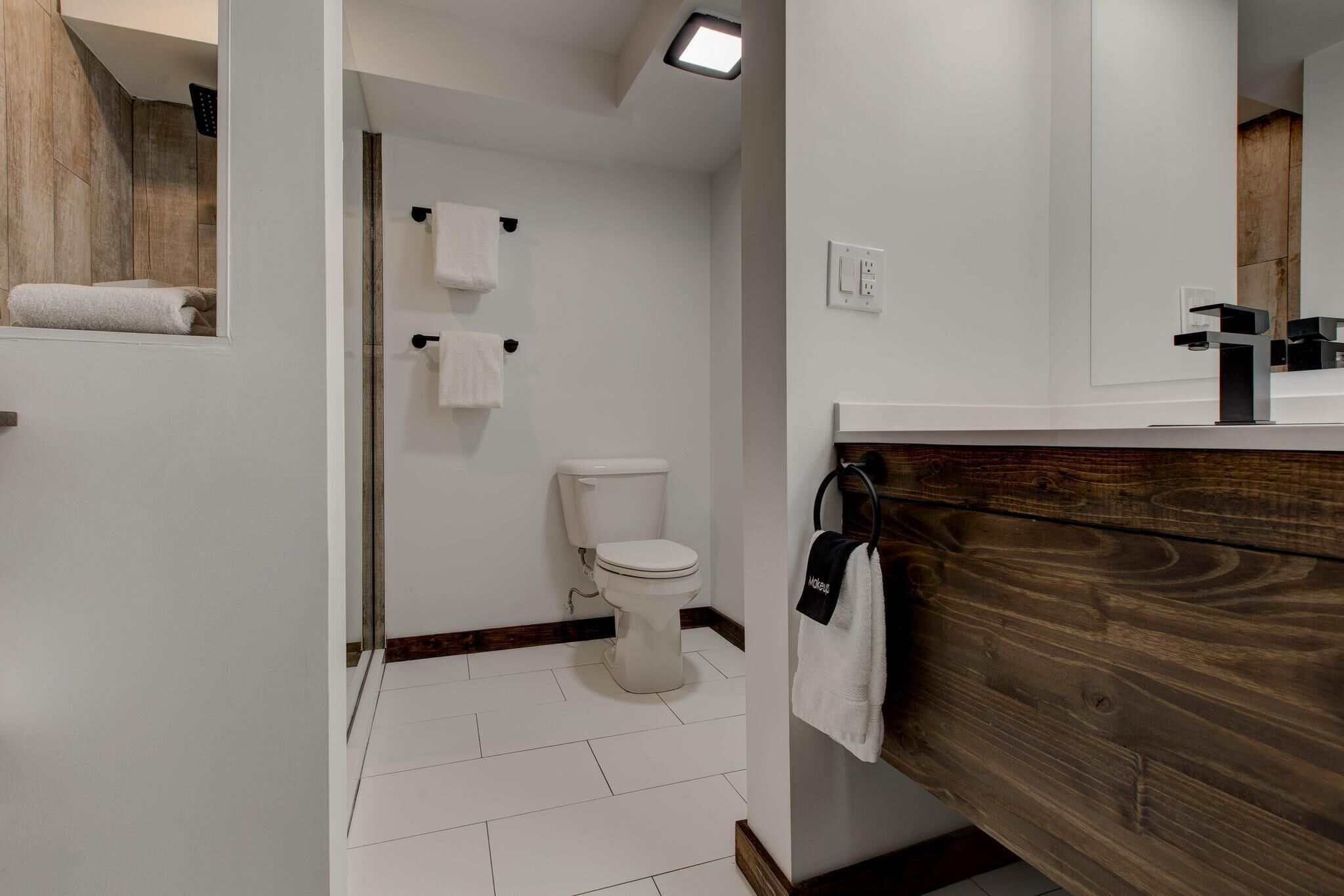 Un baño moderno con inodoro blanco, tocador de madera y espejo.