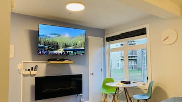 Estudio romántico | Área de sala de estar | Smart TV de 55 pulgadas con canales por cable, televisión y chimenea