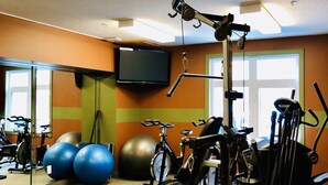 A gym with exercise equipment, a television, and exercise balls. - A Lovely Studio with Full Kitchen & AC (Canmore)
