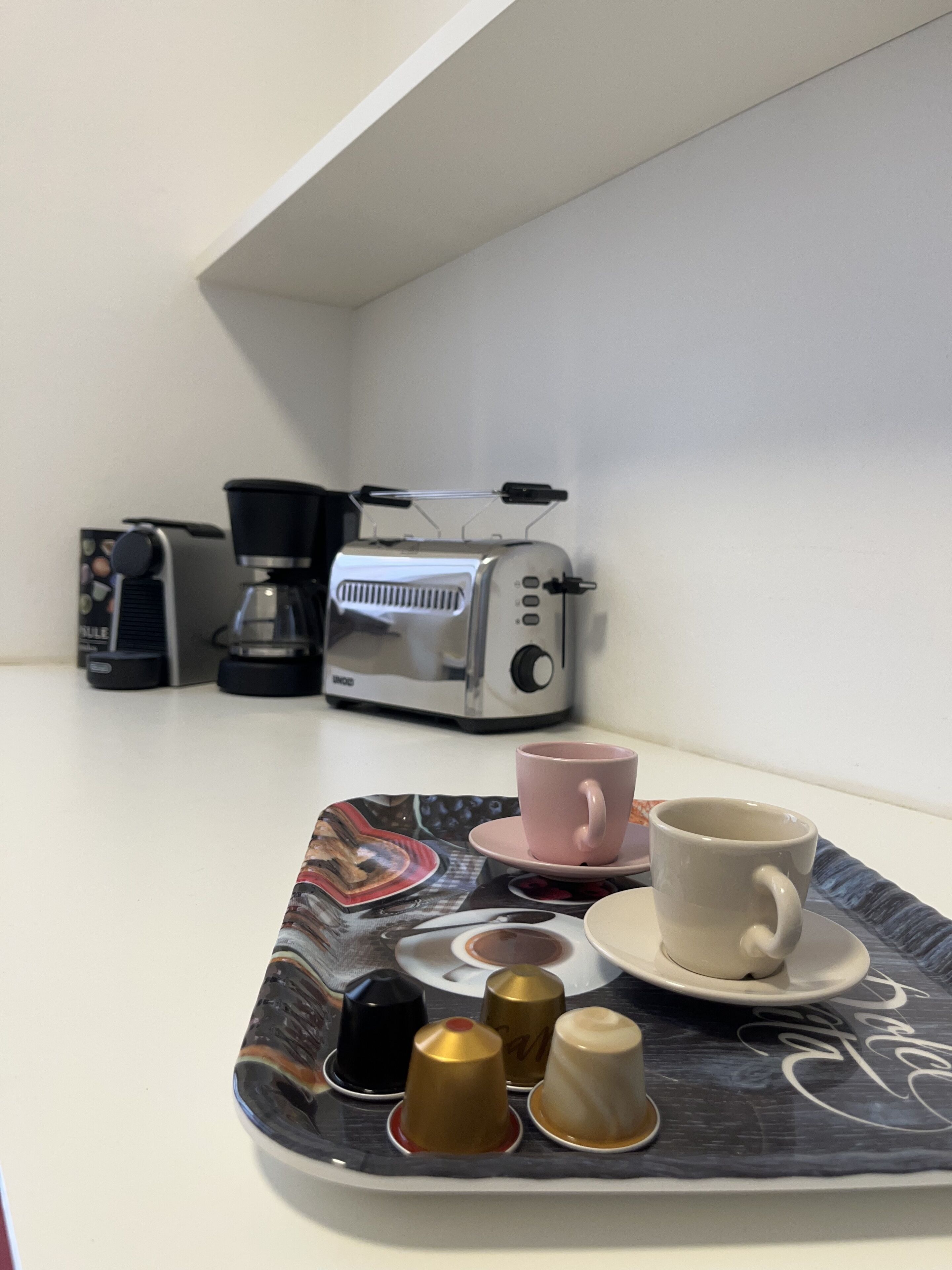 Un coin café équipé d’une machine à café, d’un grille-pain et d’un plateau avec des tasses et des condiments.