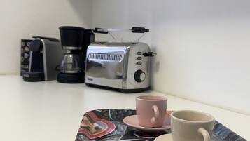 Un coin café équipé d’une machine à café, d’un grille-pain et d’un plateau avec des tasses et des condiments.