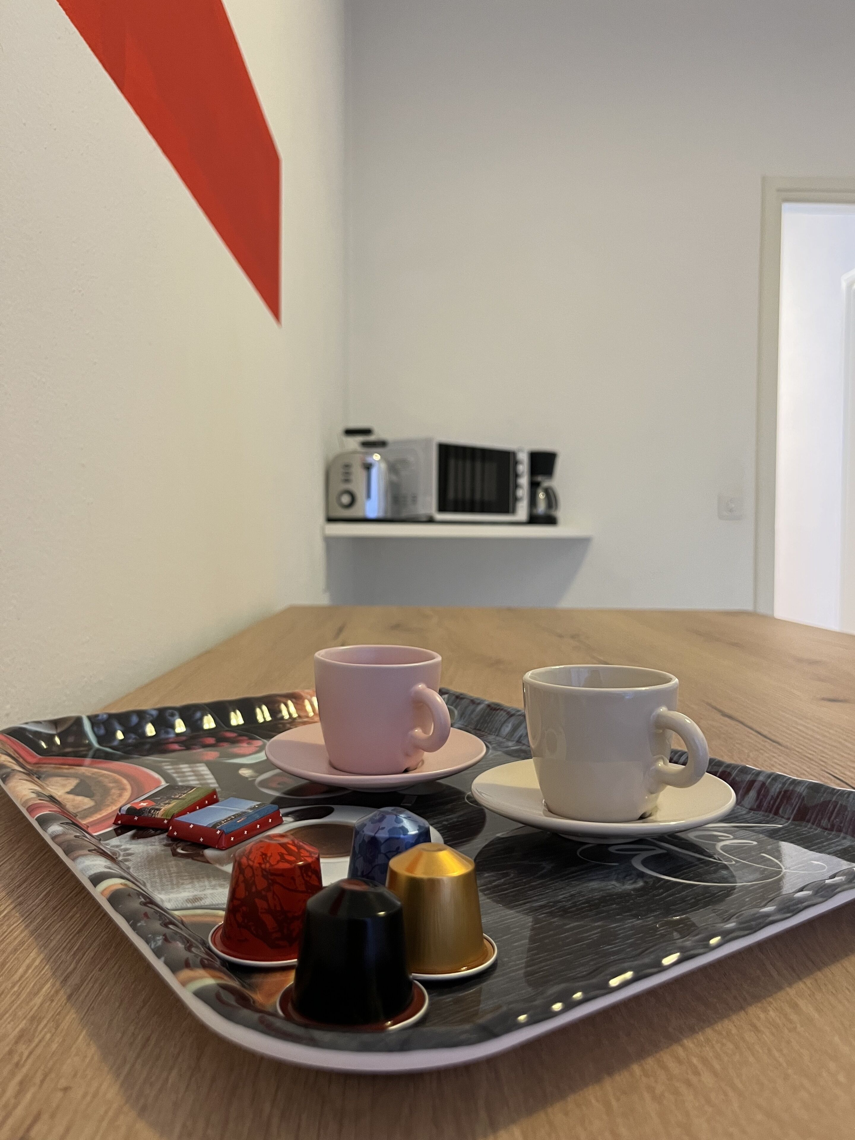 A tray with two cups and a coffee maker on a shelf.