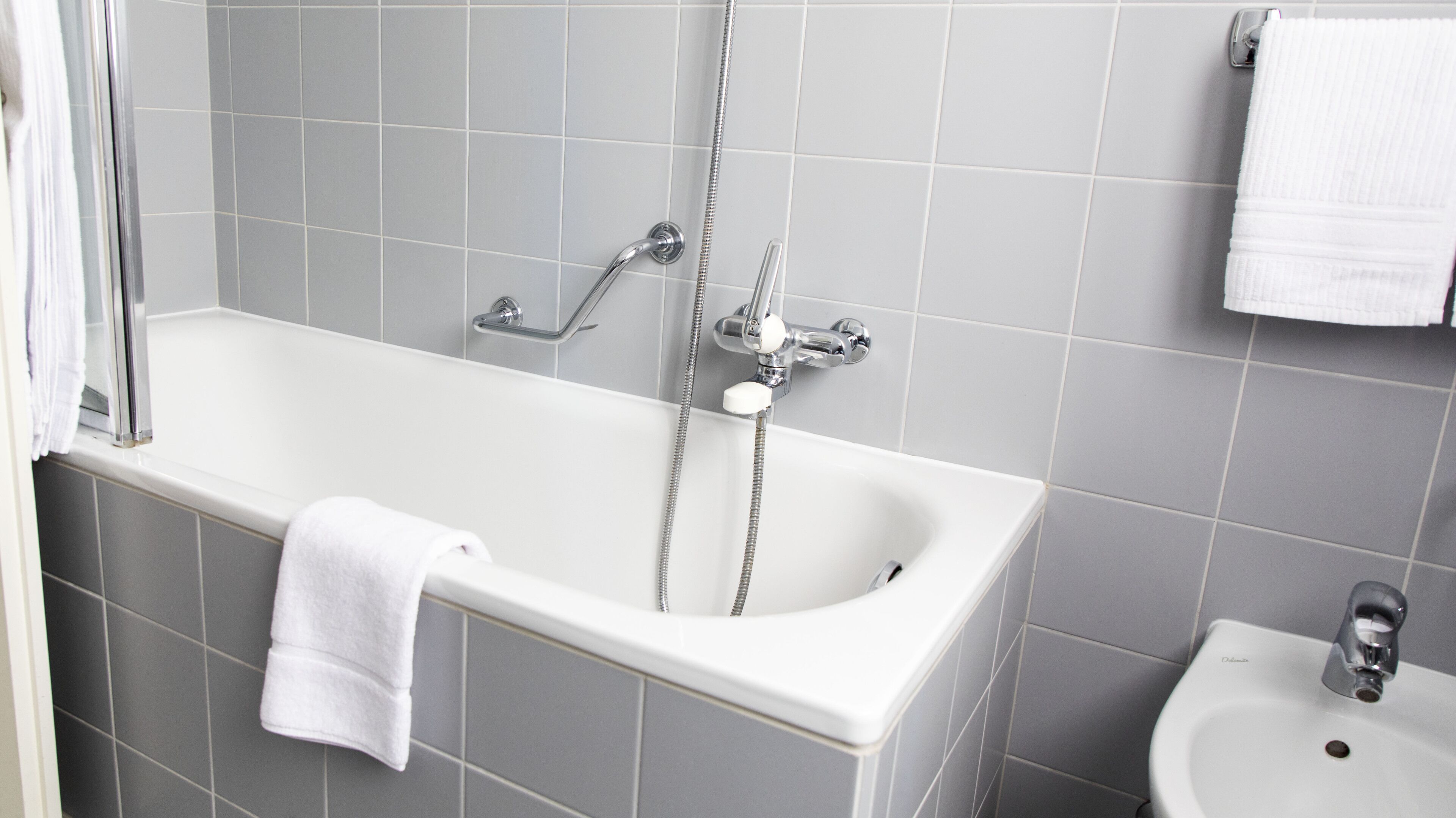 Un baño con una bañera blanca, ducha y lavamanos.