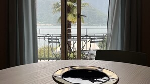 A table with a reflective tray in a room with a view of a lake and mountains through a large window with curtains. - 76thelakehouse (Melide)