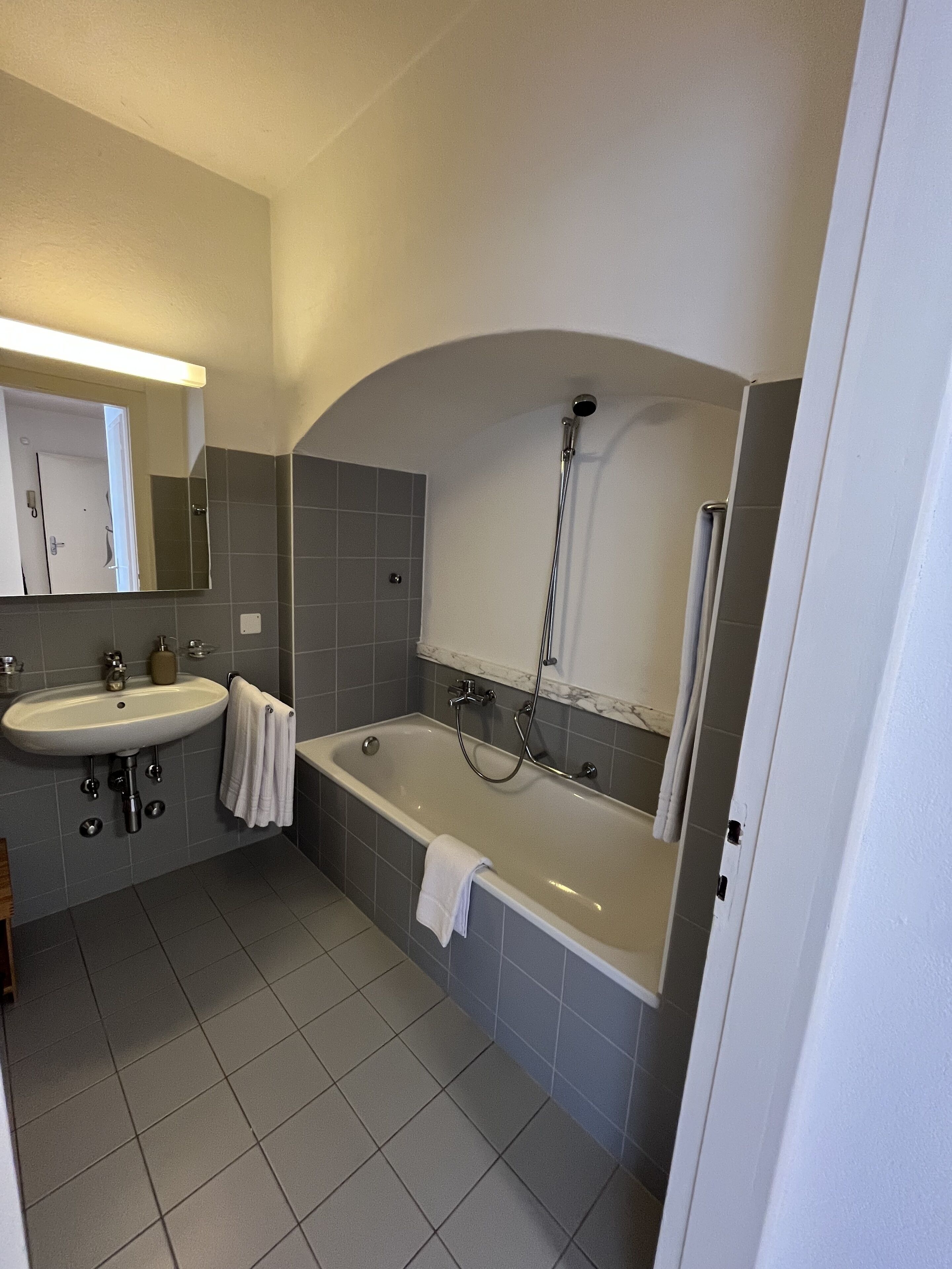 A bathroom with a sink, mirror, and bathtub.