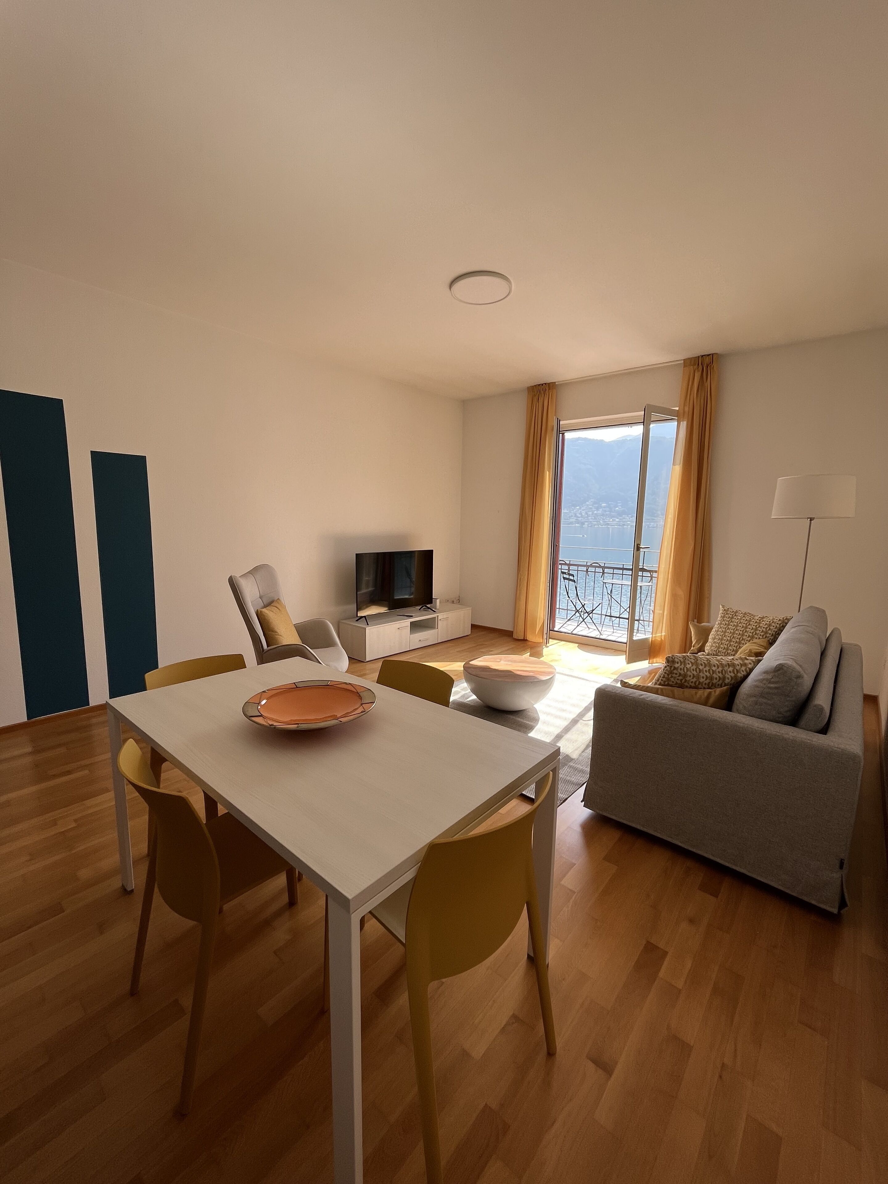 Una sala de estar moderna con comedor, sofá, televisor y un balcón con vistas.