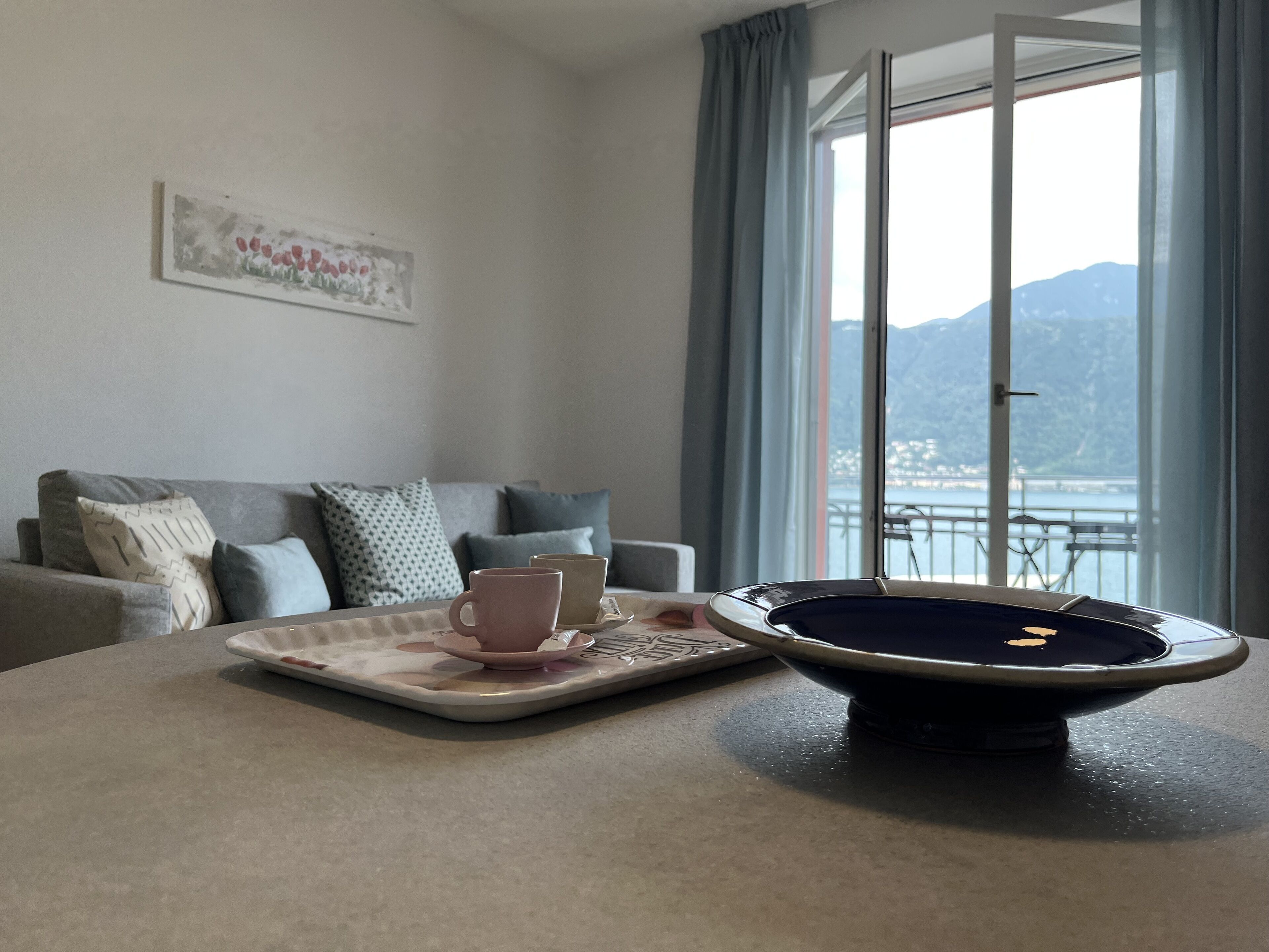 Ein Wohnzimmer mit einer Couch, einem Tisch mit Tablett, einer Schüssel und einem Bild an der Wand.