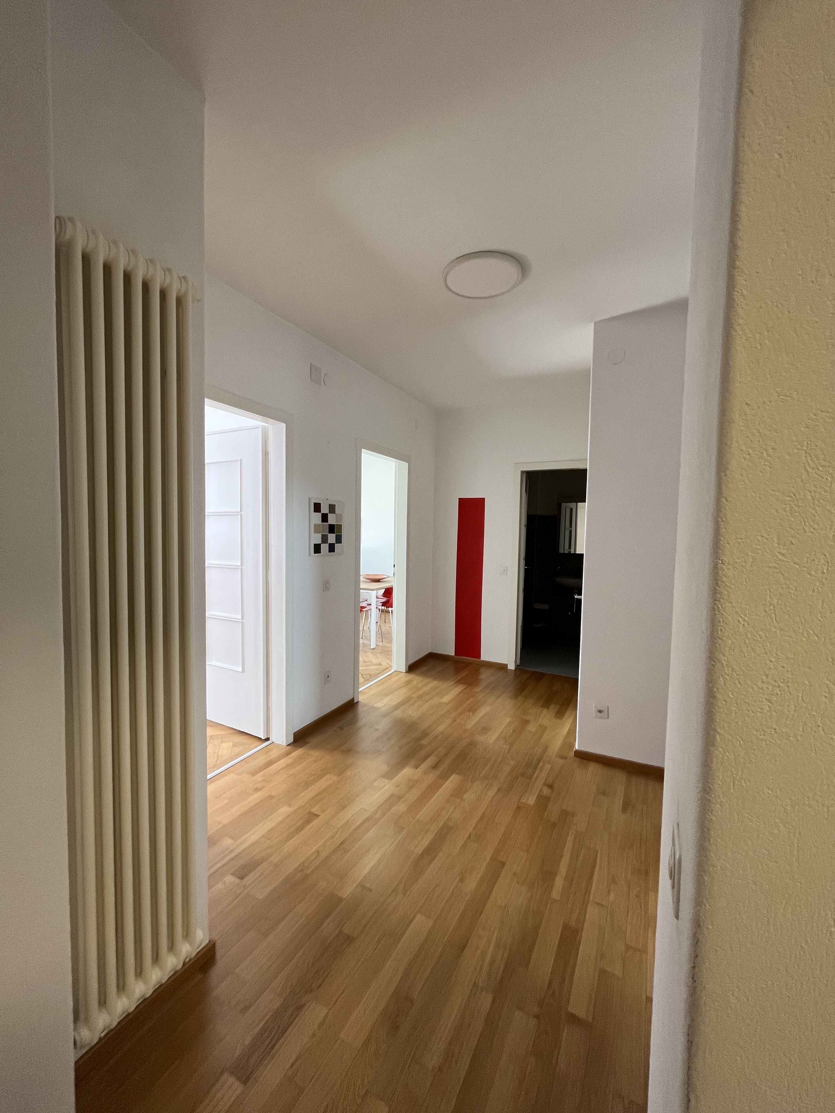 A hallway with wooden flooring, white walls, and doors leading to different rooms.