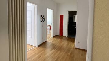 A hallway with wooden flooring, white walls, and doors leading to different rooms.