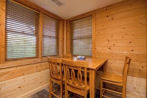 A wooden interior with a table and four chairs, large windows with blinds, and a visible air vent. - NEW Mountain Views! Prime Location yet Secluded! (Sevierville)