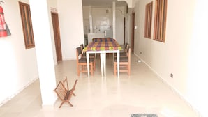A dining area with a table and chairs, a fire extinguisher, and a tiled floor. - LA CASE A MAMY (Nianing)