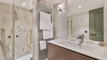 Une salle de bain moderne avec une douche à parois de verre, un grand lavabo avec un miroir et un porte-serviettes.