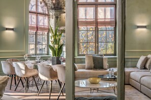 Un comedor con una mesa dispuesta para cuatro personas, sillas alrededor y un sofá con cojines.