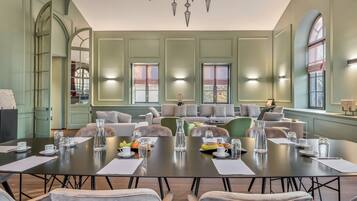Une salle de conférence spacieuse, dotée d’une longue table, de nombreuses chaises et d’un coin salon avec des canapés.