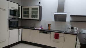 Una cucina moderna con mobili bianchi, un forno in acciaio inossidabile, un forno a microonde e una macchina da caffè.