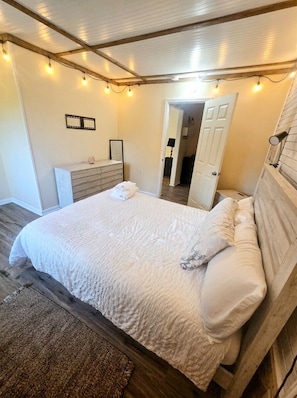 A bedroom with a bed, wooden headboard, a dresser, and a mirror. - Family Beach Retreat; Hot Tub, Private Yard and Game Room (Kings Grant)