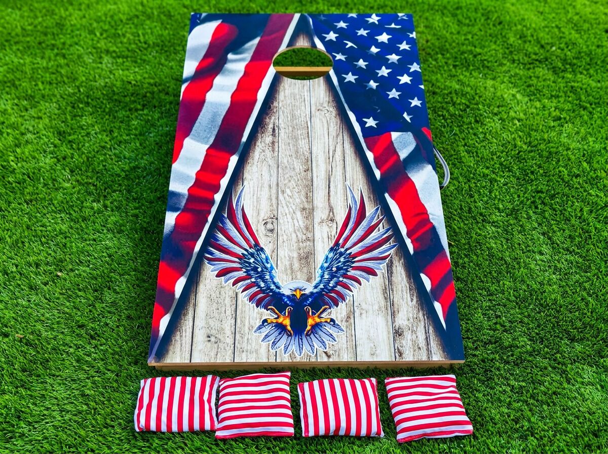A wooden structure with an eagle emblem, surrounded by red and white striped pillows on a grassy surface.