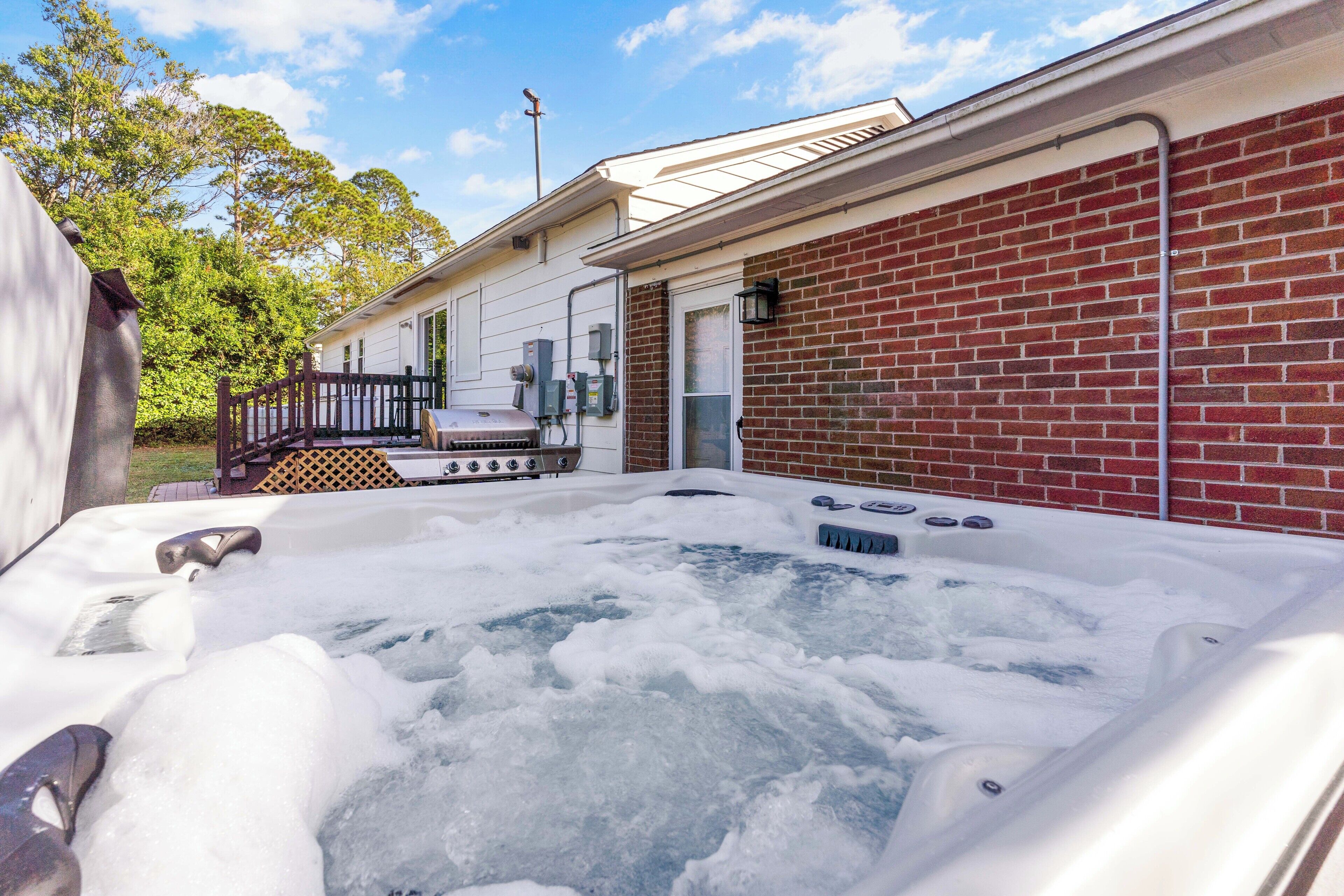 Un espace avec un jacuzzi, agrémenté d’un mur en briques et d’une terrasse en bois.