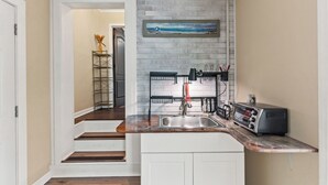 Una cocina con una escalera de madera, salpicadero de ladrillo y un tostador sobre la encimera.