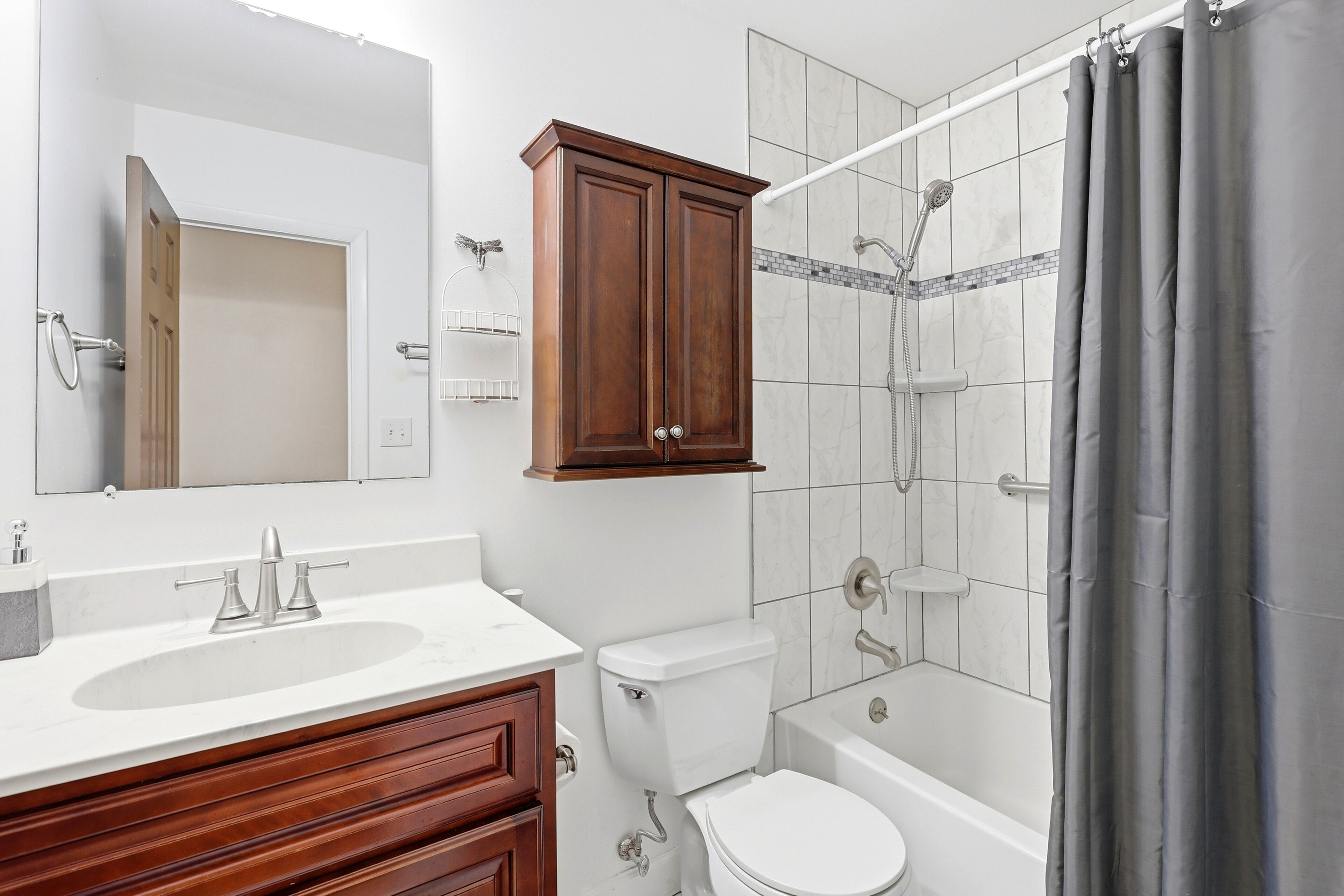 A bathroom with a wooden vanity, a toilet, a bathtub, and a shower.