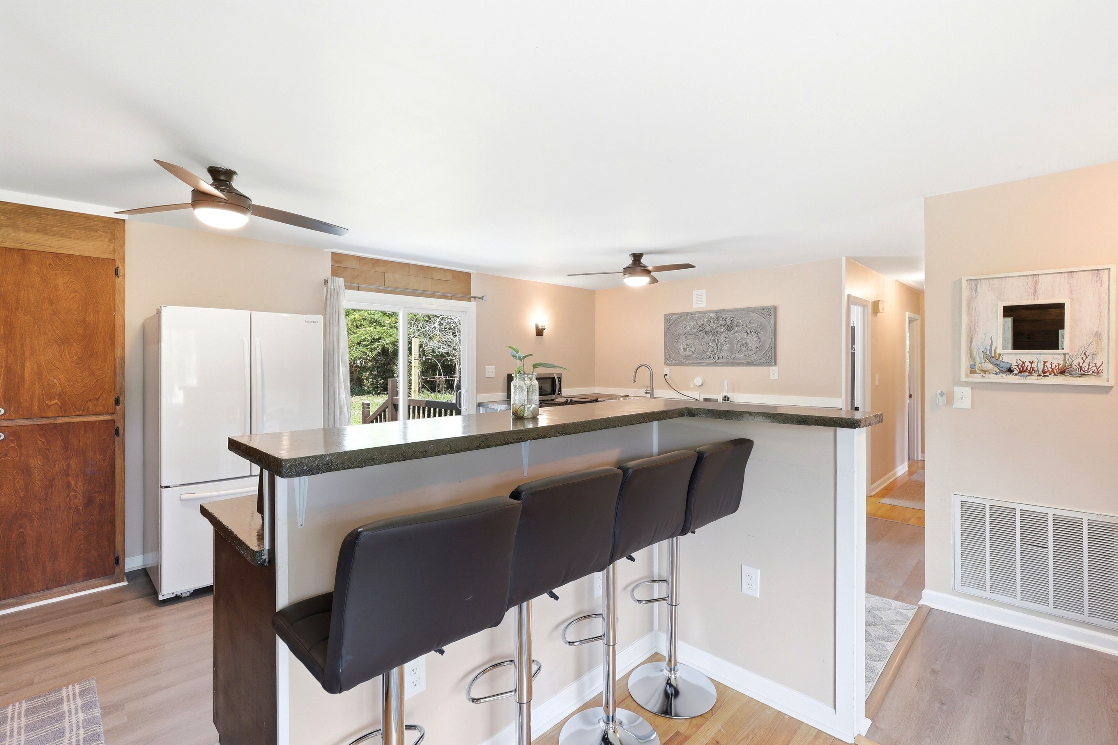 A modern kitchen with a bar area, stainless steel appliances, and a view to the outdoors.