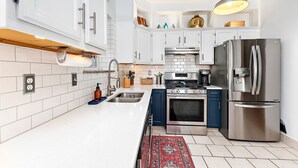 Eine moderne Küche mit weißen Schränken, einem Edelstahlkühlschrank und einem eingebauten Backofen.