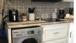 A compact kitchen with a washing machine, a microwave, and a coffee maker. - Poppy Seed Cottage (Canyon Lake)
