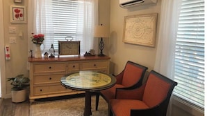 A room with a wooden dresser, a round glass table, and a single orange chair. - Poppy Seed Cottage (Canyon Lake)