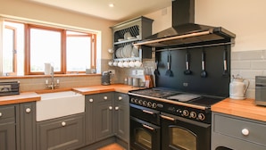 Une cuisine moderne avec des meubles gris, une cuisinière noire et une fenêtre aux cadres en bois.