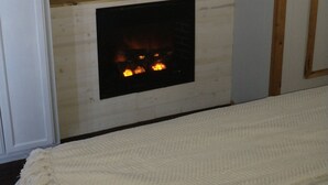 A room with a fireplace, a mounted television, and a wooden wall.