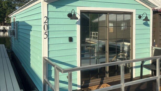 A turquoise house with the number 205, a porch, and a window.