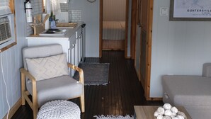 A compact, well-lit room with a kitchenette, a ceiling fan, and a bed.