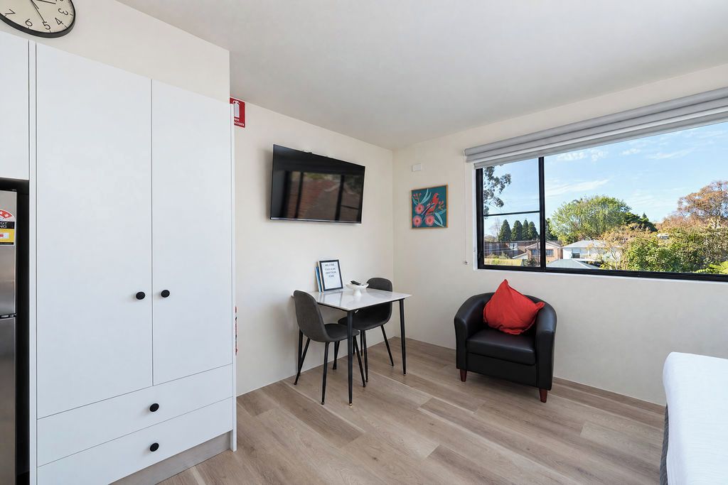 A modern room with a dining area, a sofa, a TV, and a window with a view.