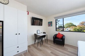 Une chambre moderne dotée d’un coin repas, d’un canapé, d’une télévision et d’une fenêtre offrant une vue agréable.