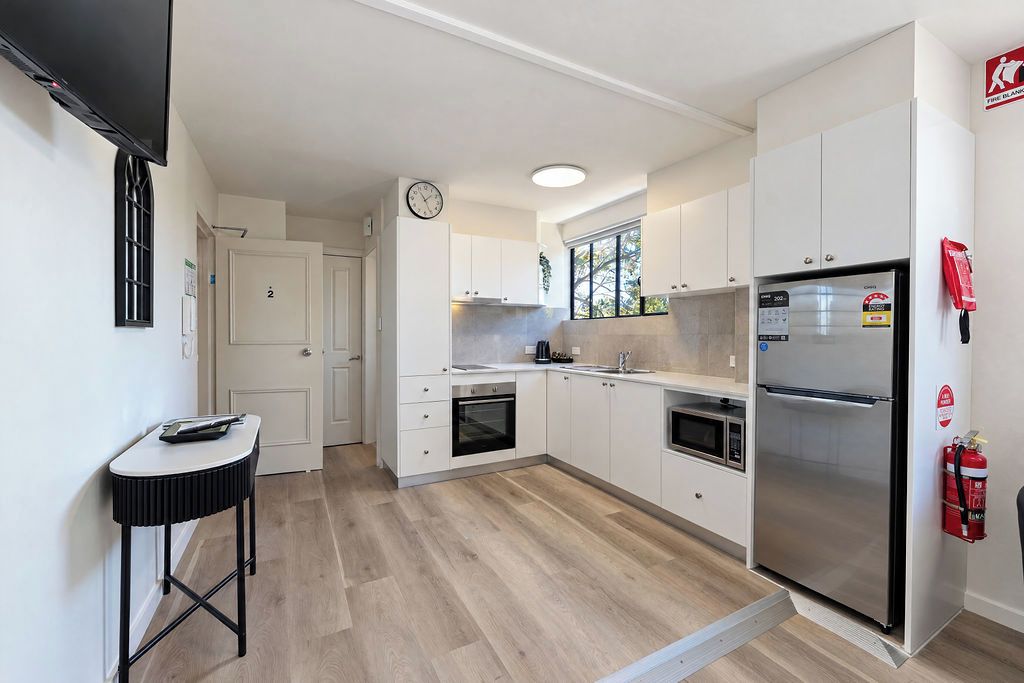 A modern kitchen with white cabinetry, a stainless steel refrigerator, and a built-in oven.