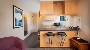 Una cocina moderna con gabinetes de madera, una barra con taburetes y un refrigerador.