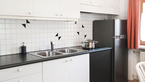 Eine moderne Küche mit weißen Schränken, schwarzen Arbeitsplatten und einem Edelstahl-Kühlschrank.