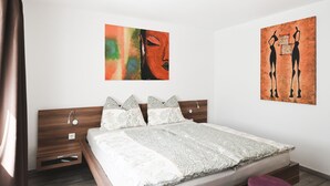 Ein modernes Schlafzimmer mit einem hölzernen Bett, zwei Nachttischen, einem großen Fenster und zwei violetten Hocker.