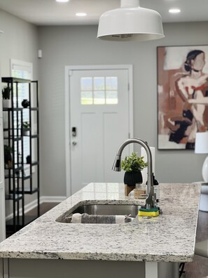 Enjoy cooking in this well-equipped kitchen with a granite countertop, stainless steel sink, and ample storage.