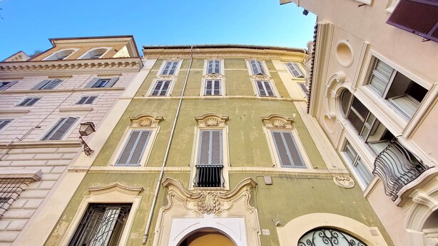 A multi-story building with ornate architectural details, including decorative moldings and a series of windows with shutters. - Youroom - Coppelle (Rome)